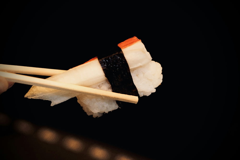 a piece of sushi with chopsticks sticking out of it