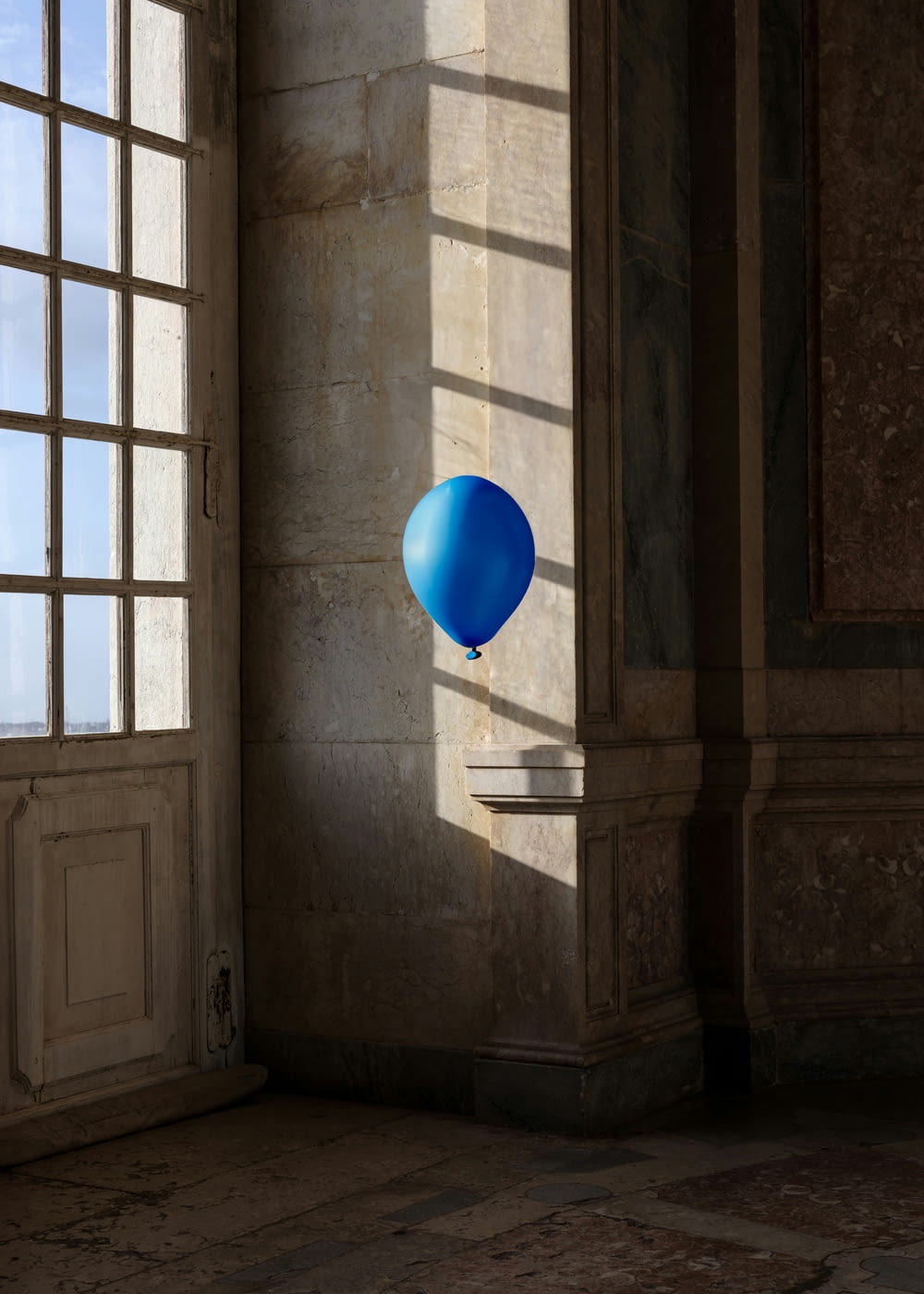 a blue balloon floating in the air next to a window