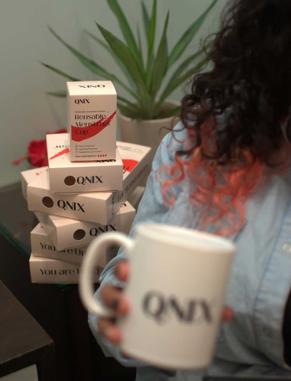 a woman holding a coffee mug in front of a stack of boxes