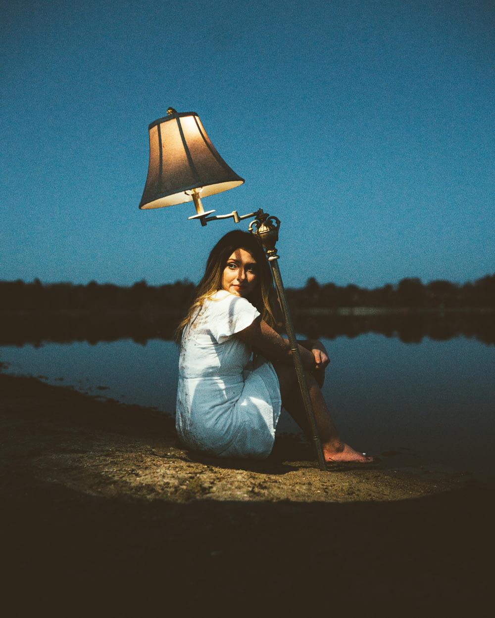 a woman sitting on the ground next to a lamp