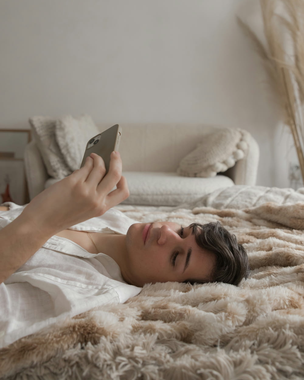 a person laying on a bed looking at a cell phone