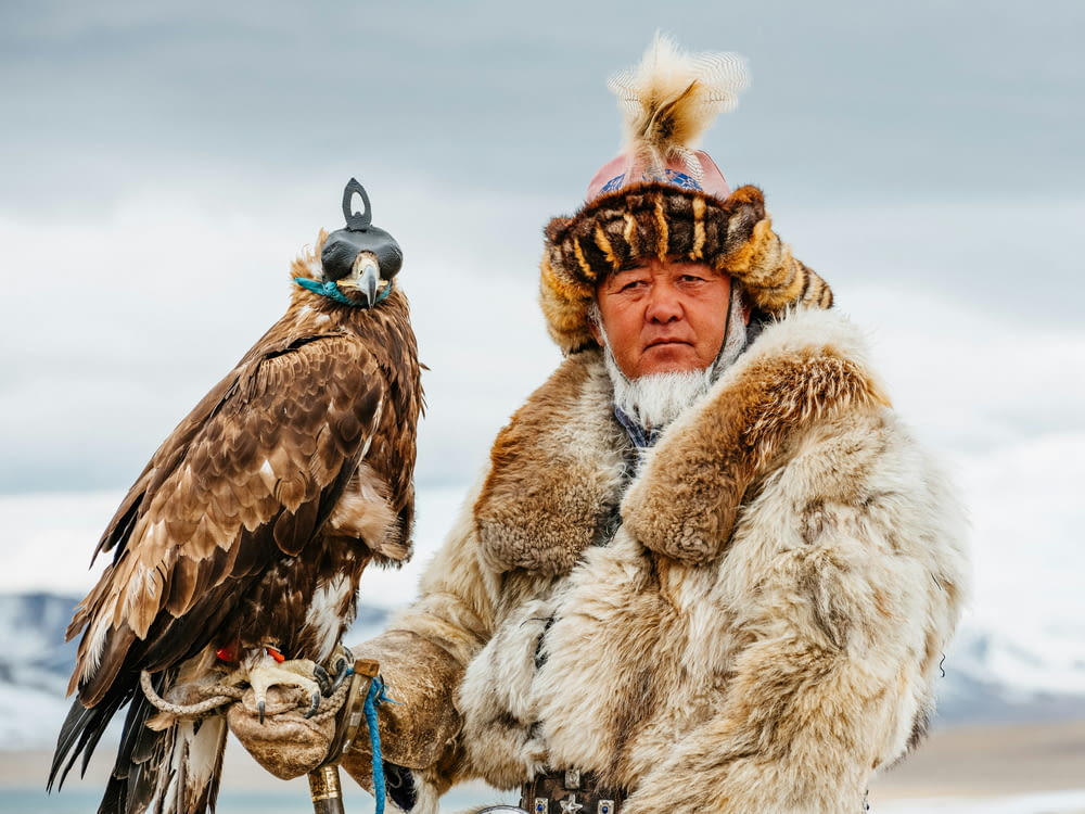 a man in a fur coat holding a bird of prey