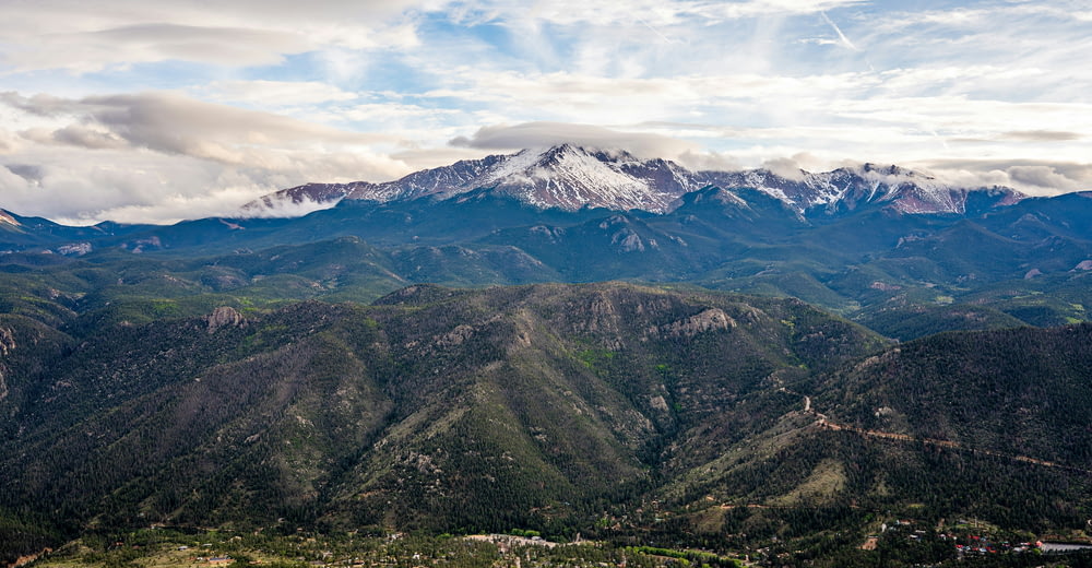 a scenic view of a mountain range with snow capped mountains in the distance