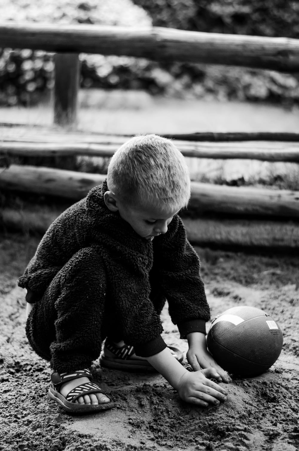 um menino brincando com uma bola na areia