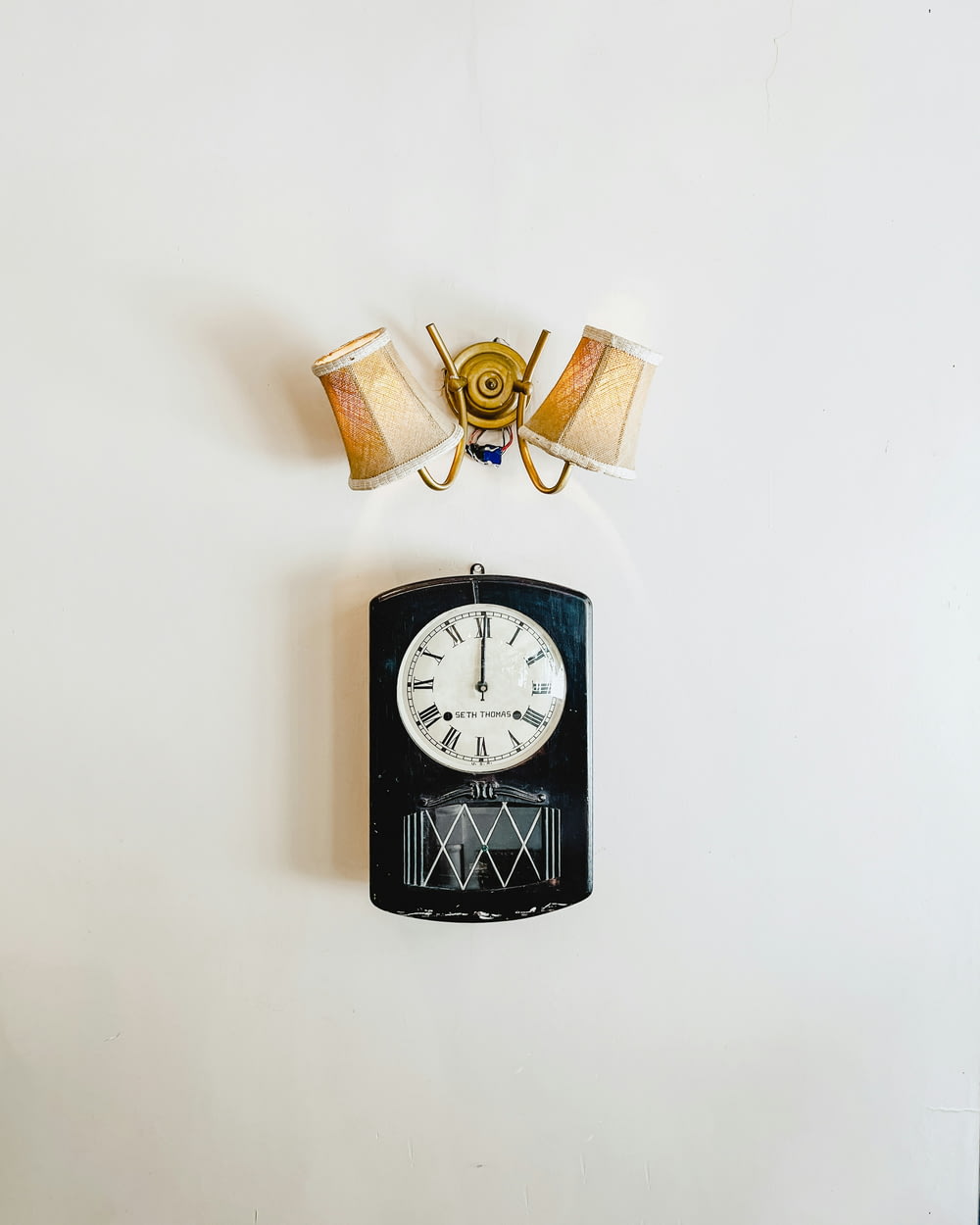 a wall mounted clock with two lamps on top of it