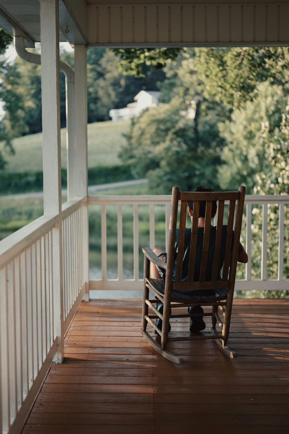 a person sitting on a rocking chair on a porch