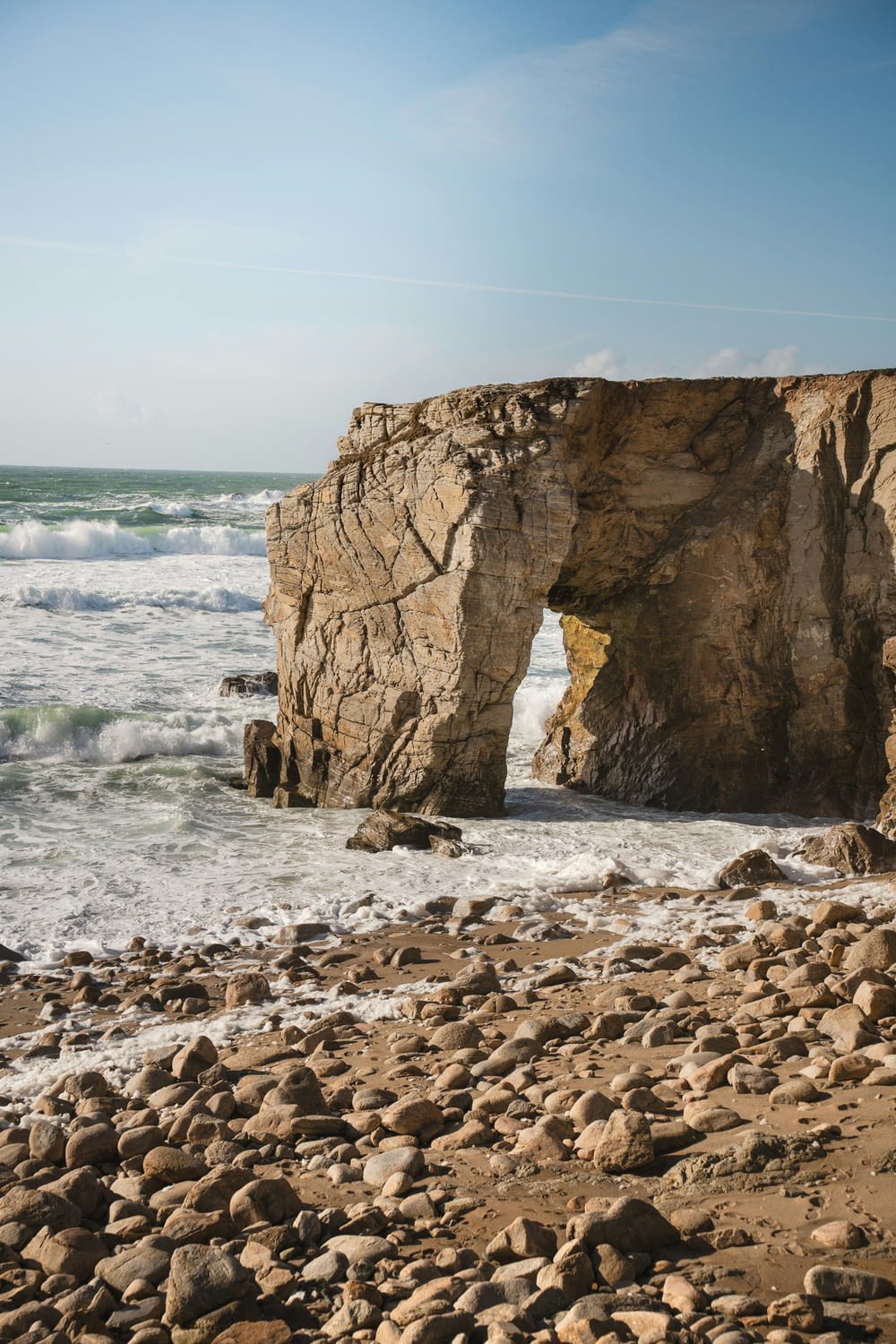 その真ん中に大きな岩のアーチがある岩だらけのビーチ