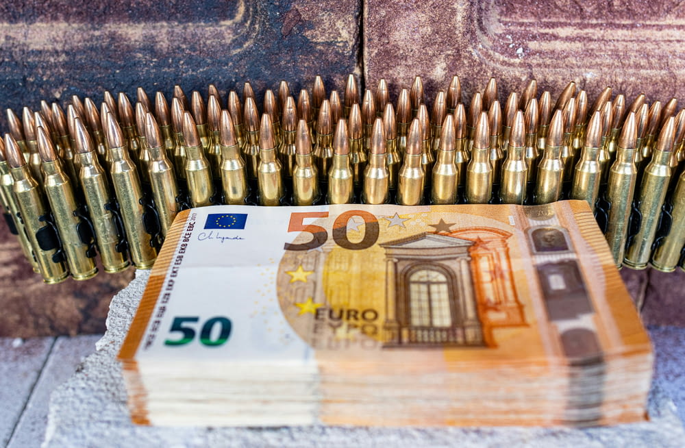 Un montón de casquillos de bala encima de una pila de billetes de 50 euros