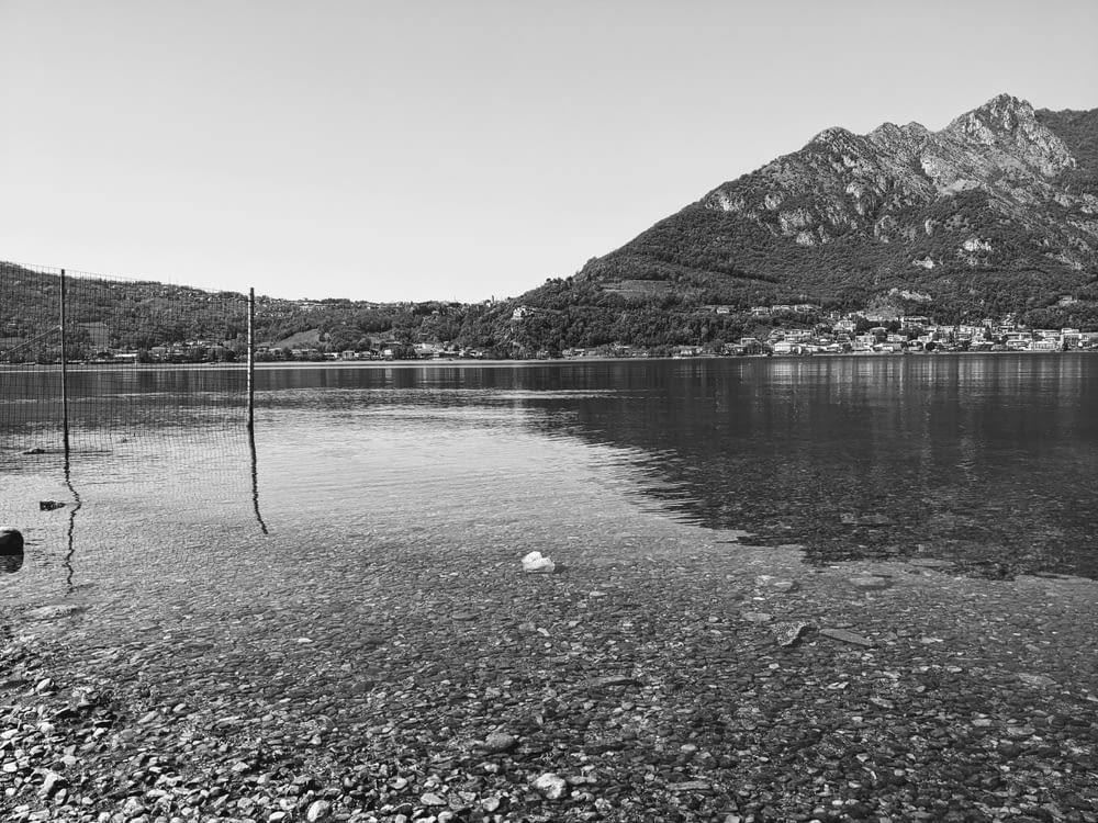 Una foto en blanco y negro de un lago con montañas de fondo