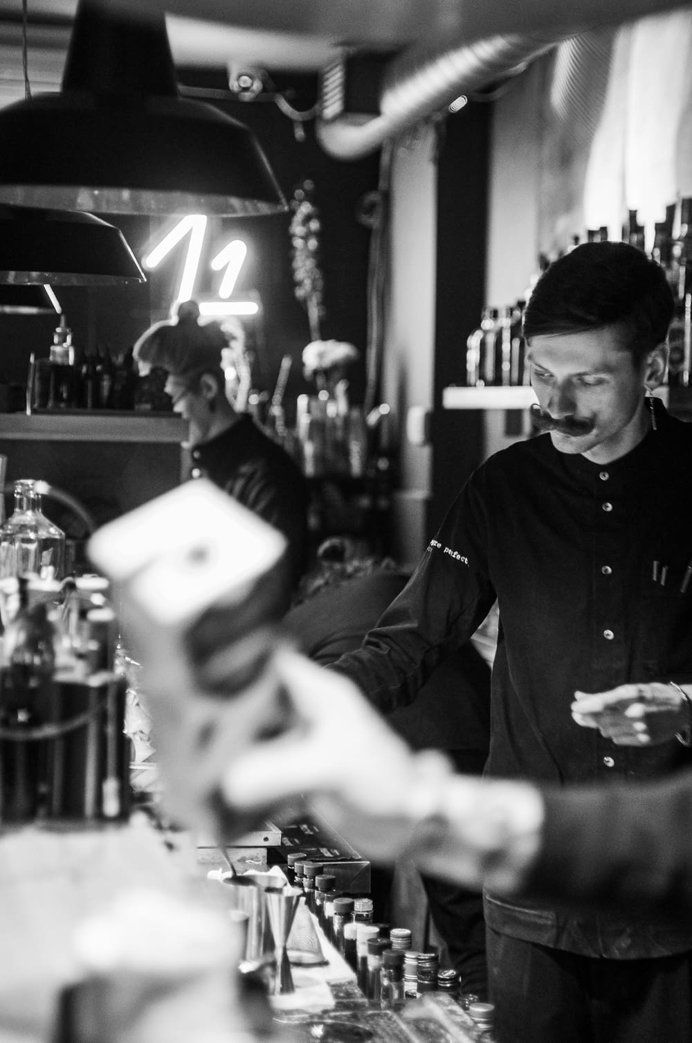 a black and white photo of a man behind a bar