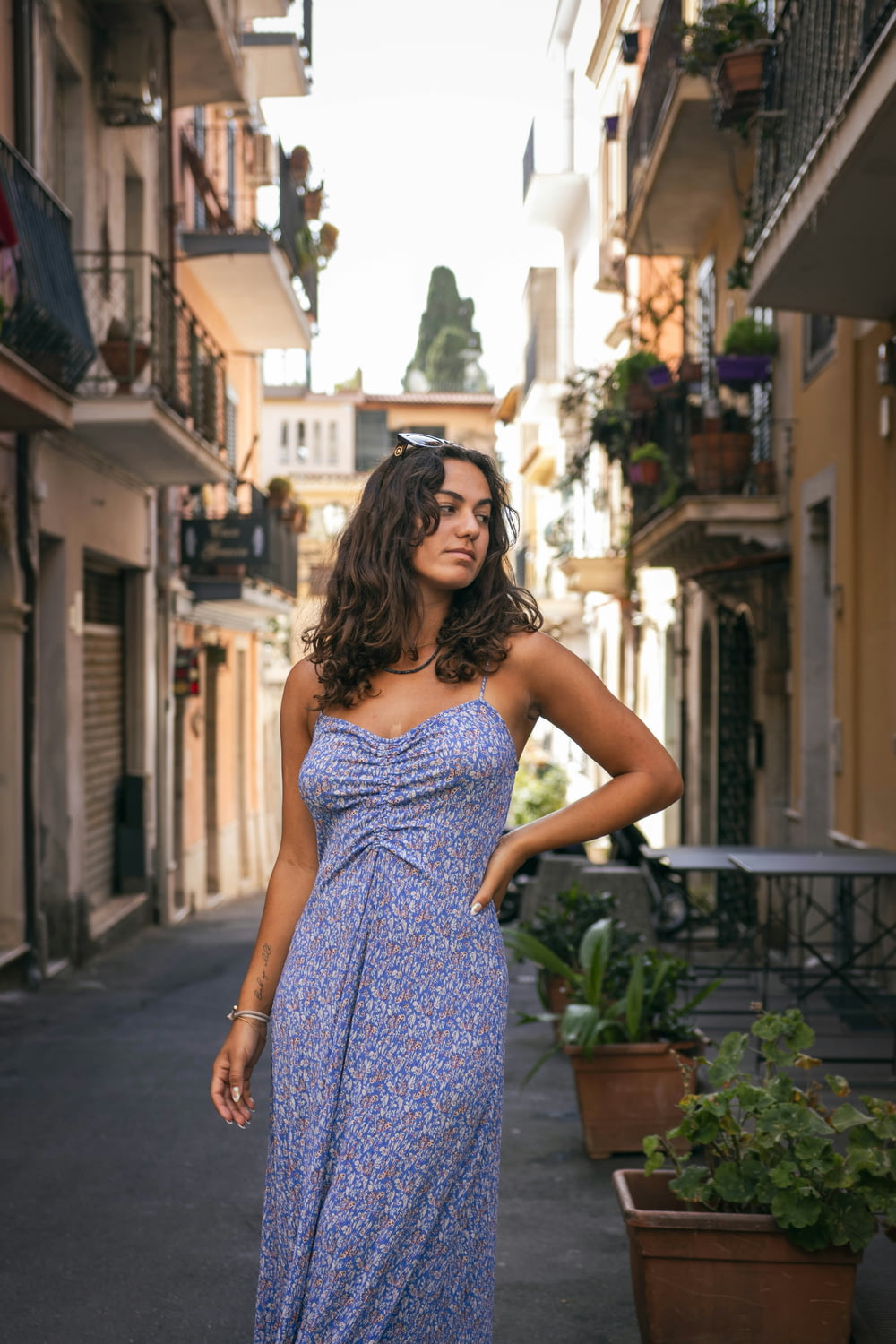 a woman in a blue dress standing on a street