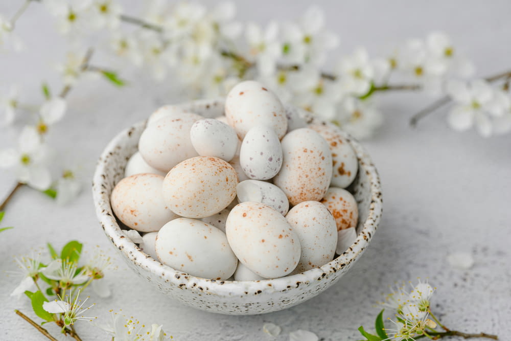 a bowl filled with white and brown speckled eggs