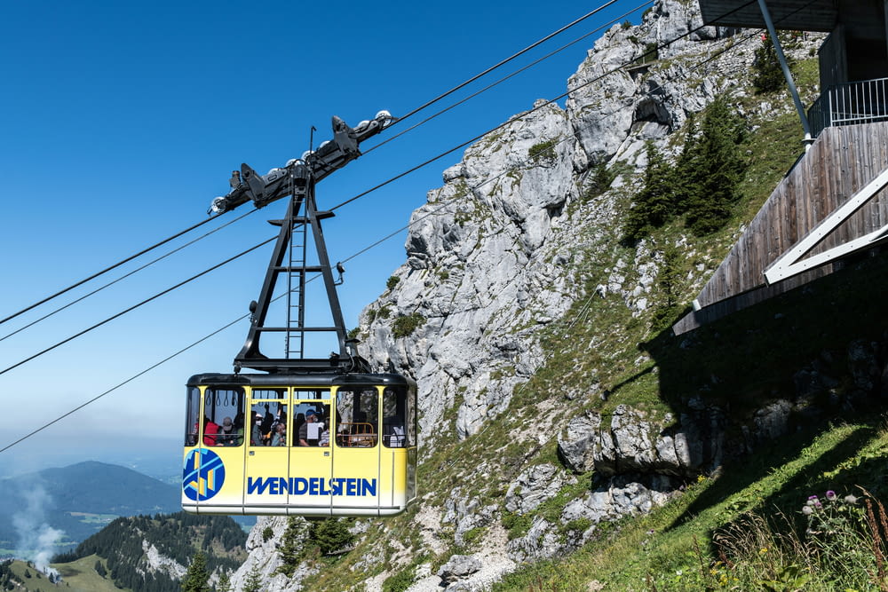 a cable car with passengers going up a mountain