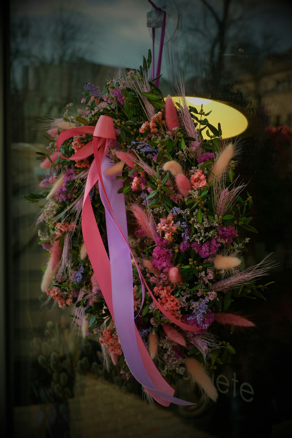 a wreath with pink ribbons hanging from it