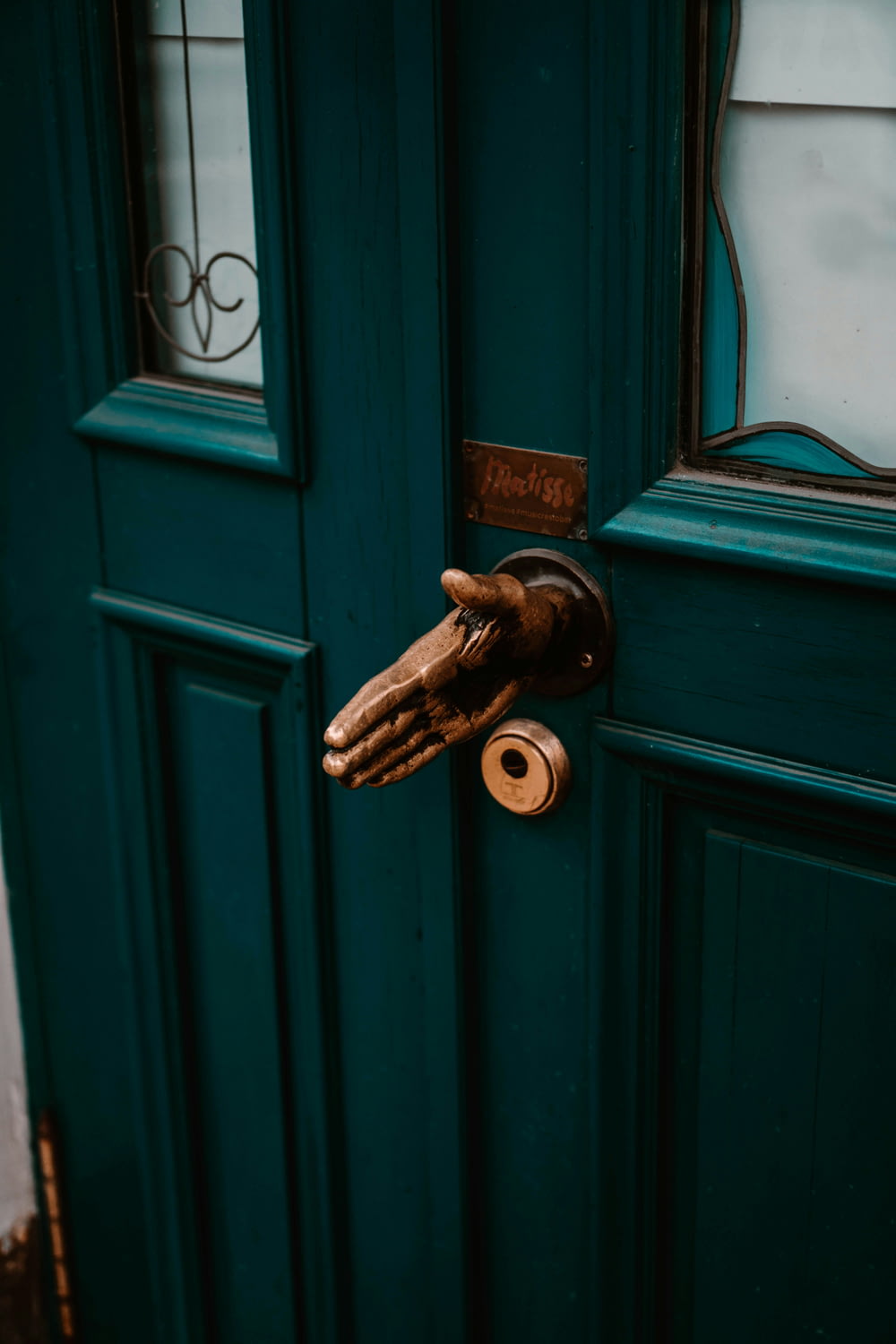 a hand holding a door handle on a green door