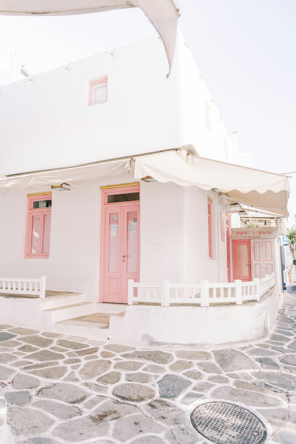 분홍색 문과 흰색 울타리가 있는 흰색 건물
