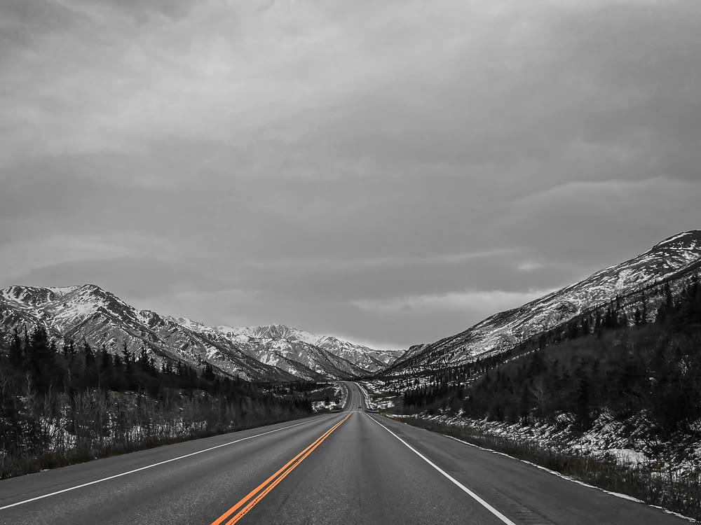 Una foto en blanco y negro de una carretera con montañas de fondo
