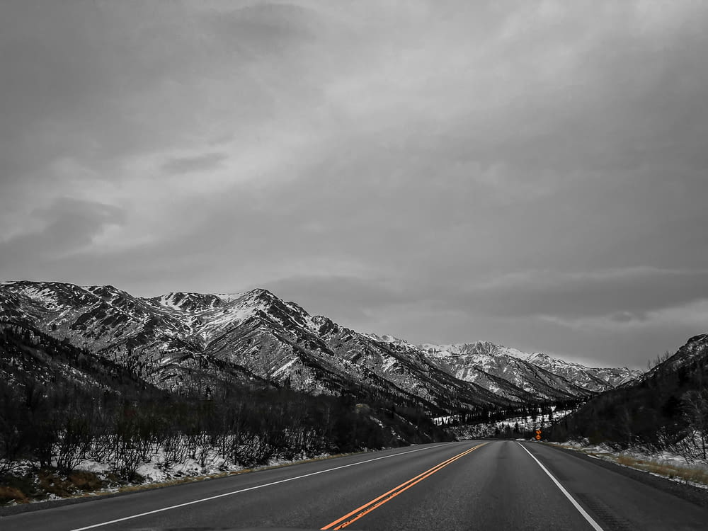 Una foto en blanco y negro de una carretera con montañas de fondo