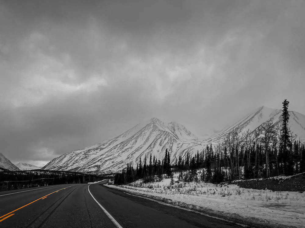 une photo en noir et blanc d’une route avec une montagne en arrière-plan