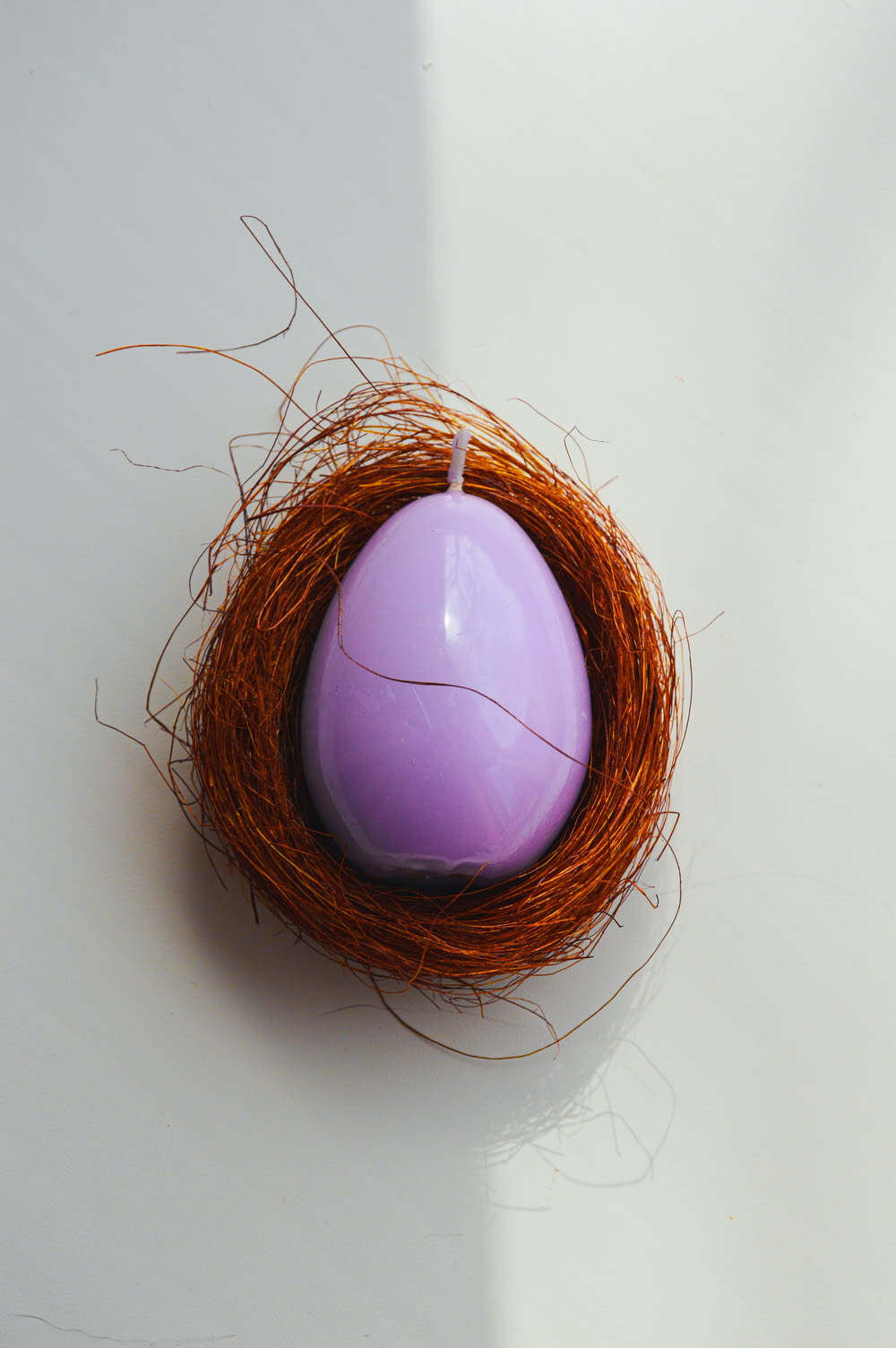 a purple egg sitting in a nest on a table