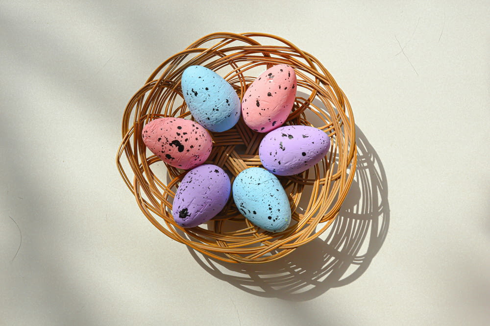 a basket filled with colorful speckled eggs on top of a table