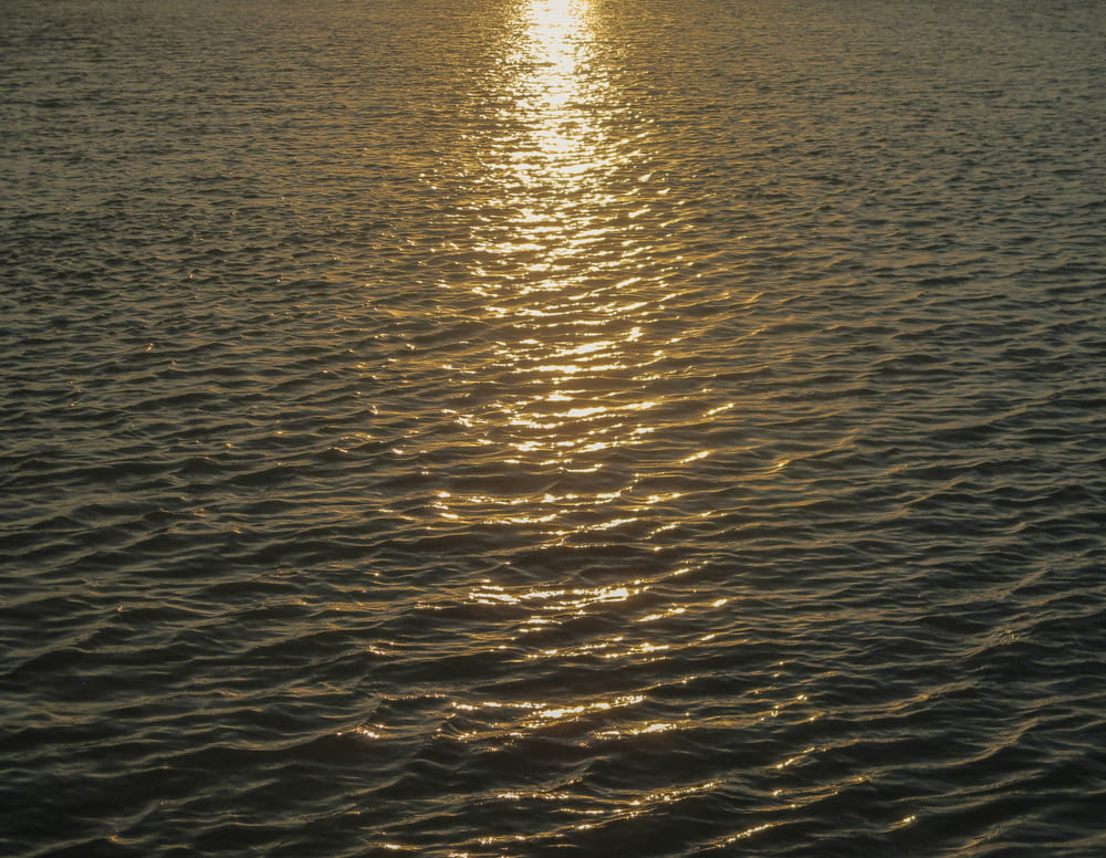 a large body of water with a sunset in the background