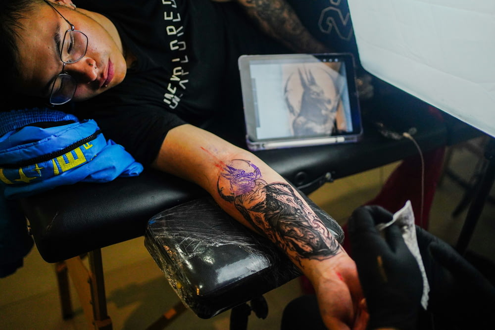 a man with a tattoo on his arm sitting in a chair