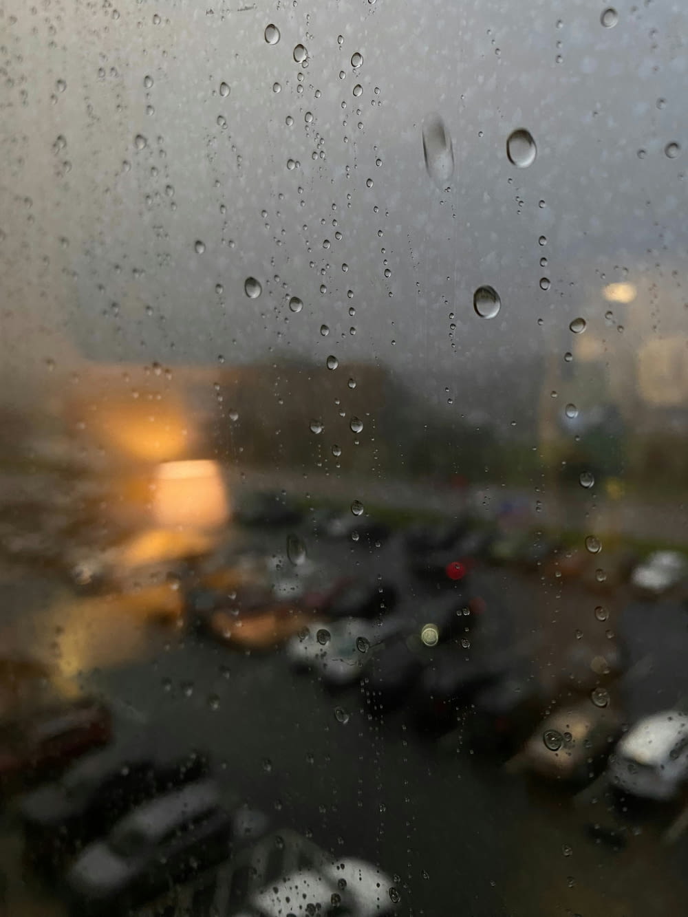 a view of a parking lot through a rain covered window