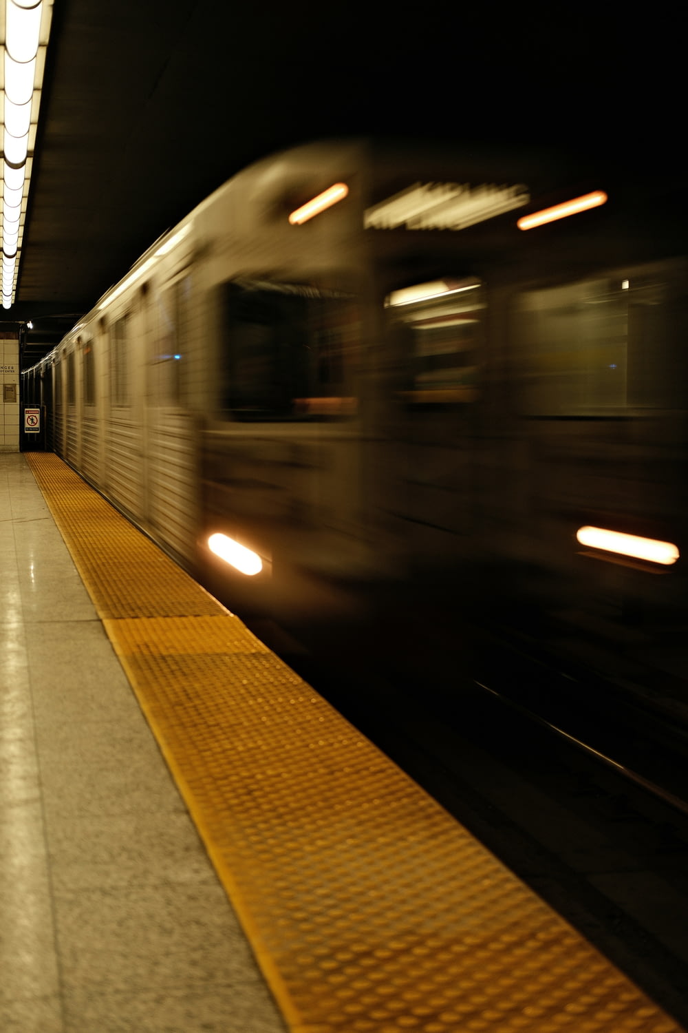 a subway train speeding past a platform at night