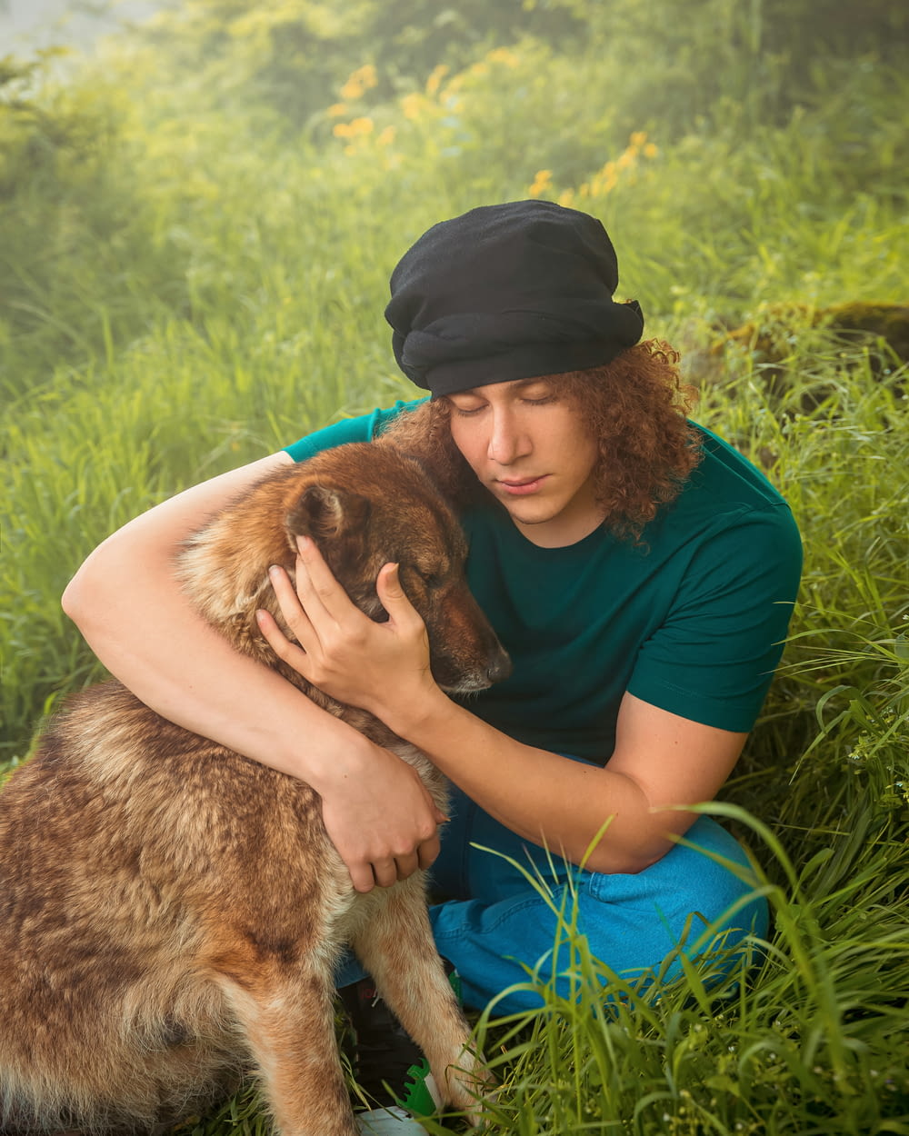 a man sitting in the grass with his dog