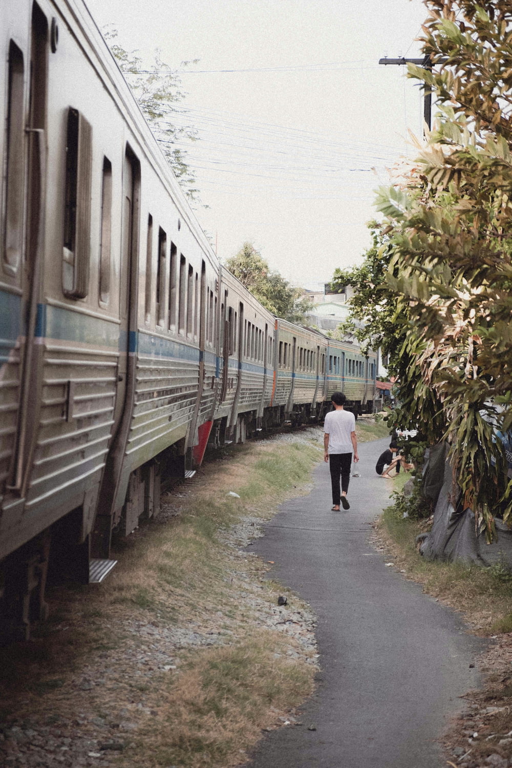 a person walking down a path next to a train