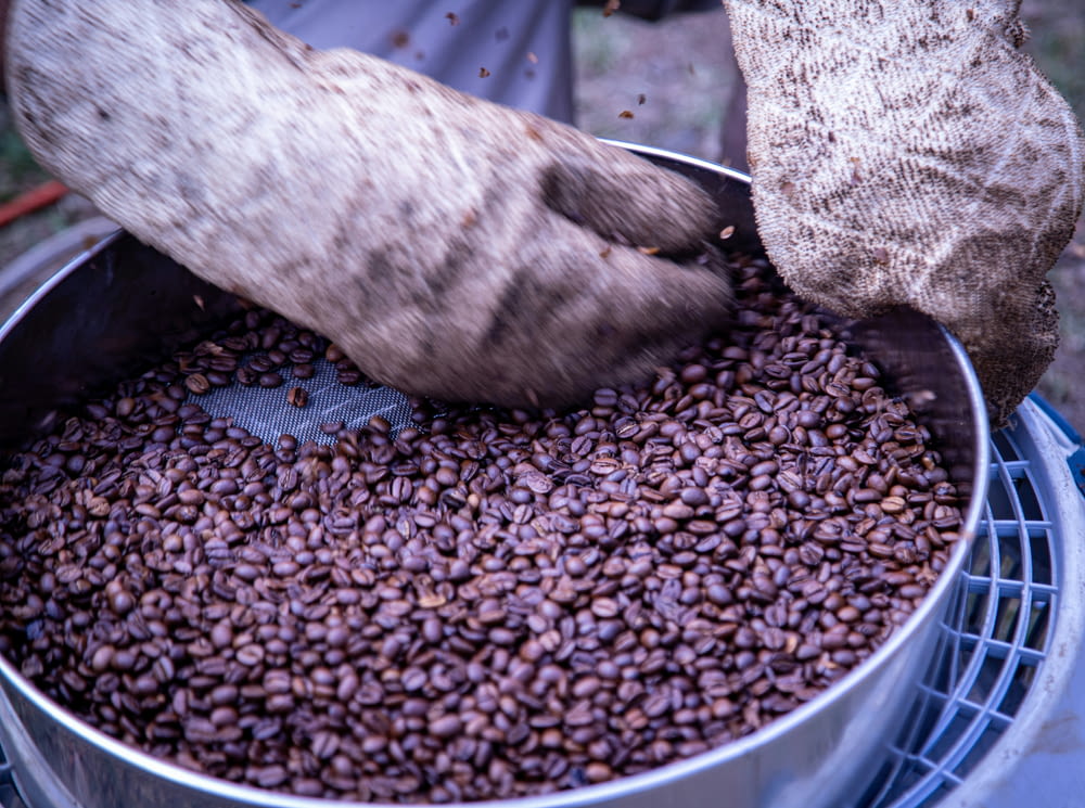 a person scooping coffee beans into a pot