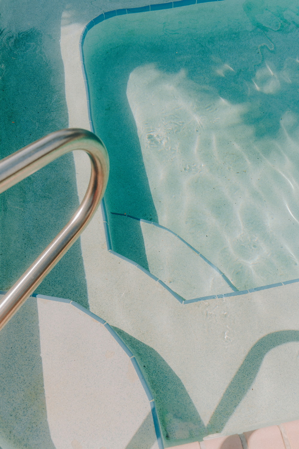 a close up of a pool with a metal hand rail