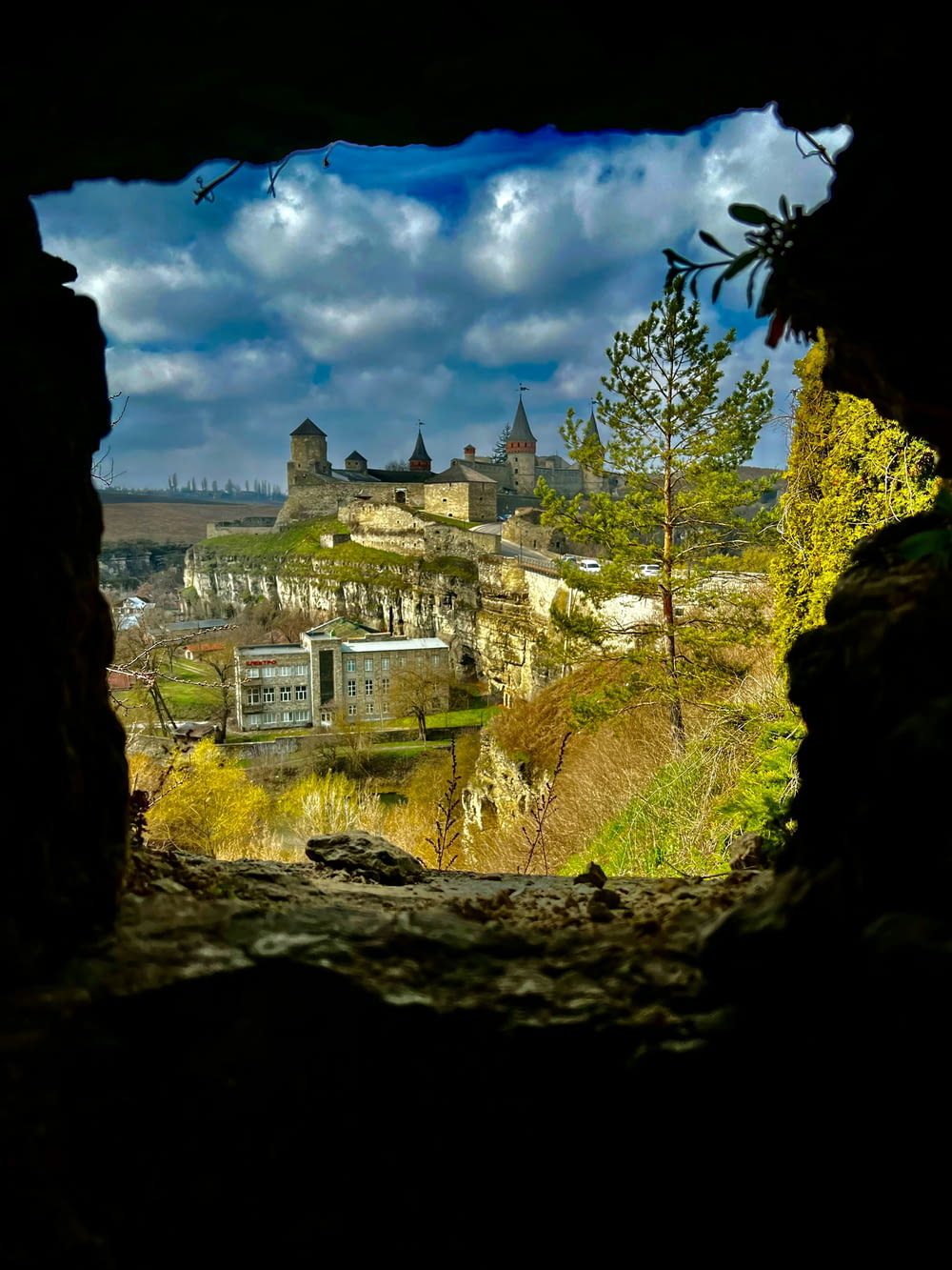 a view of a castle through a hole in a rock