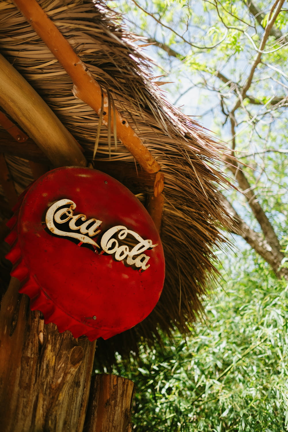 a coca cola sign hanging from a thatched roof