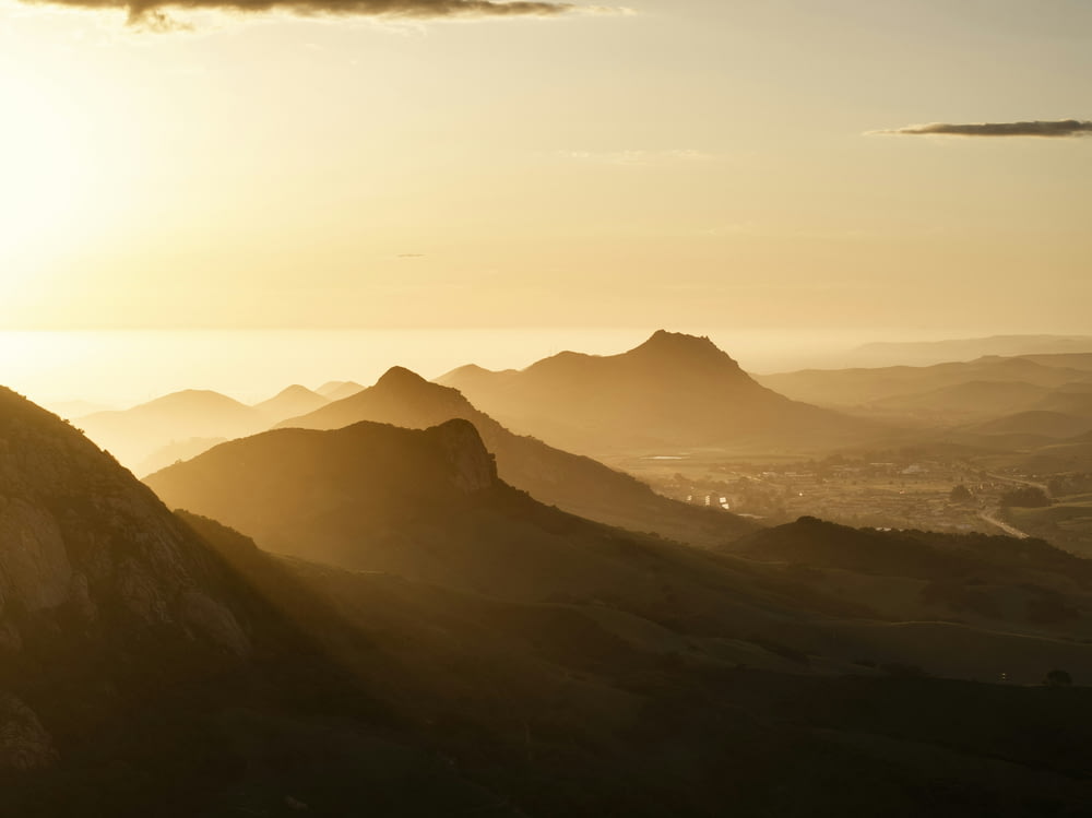 uma pessoa em pé no topo de uma montanha ao pôr do sol