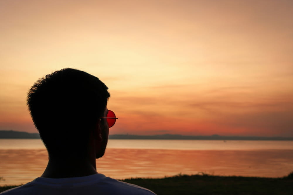 a man wearing sunglasses looking out at the water