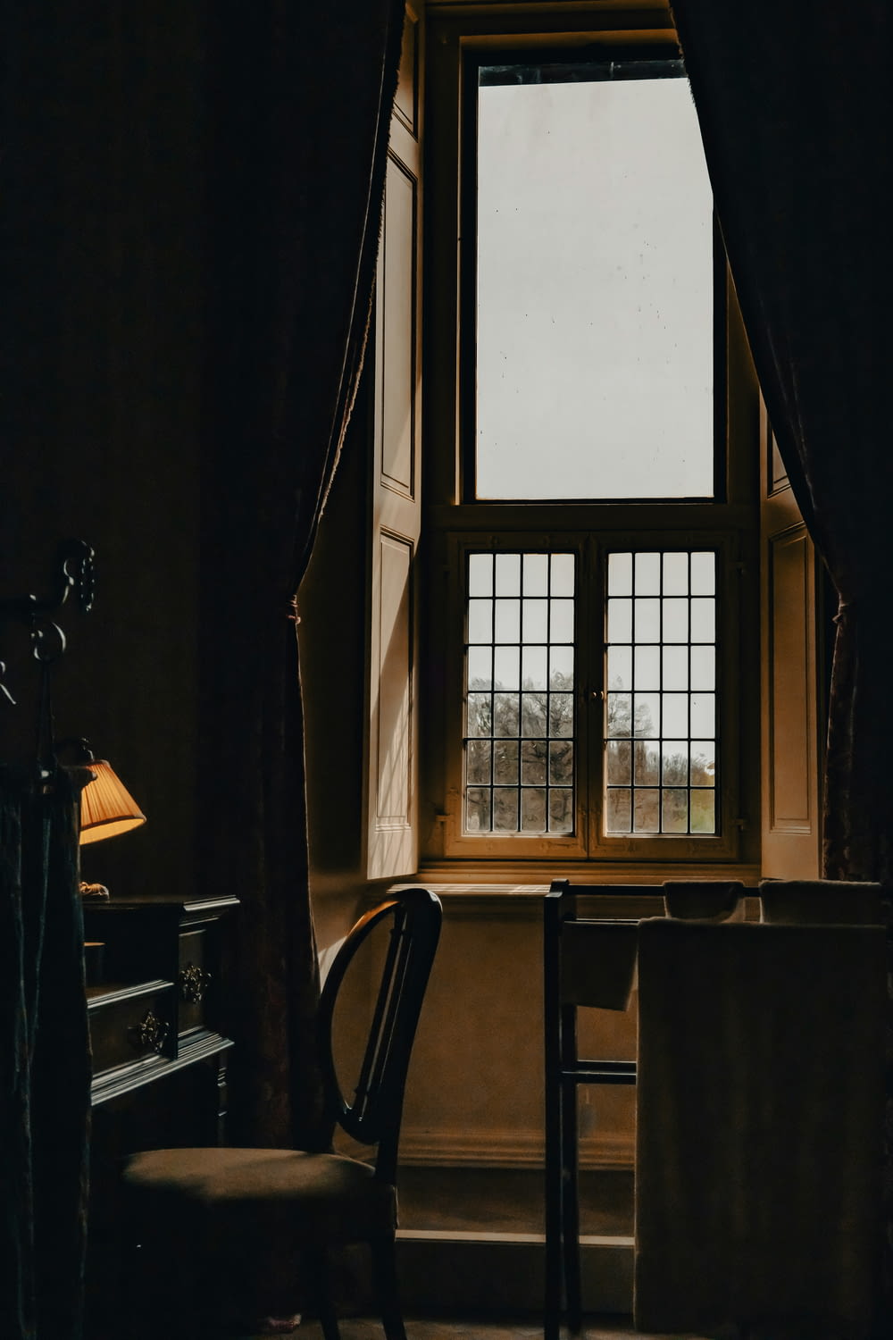 a dark room with a chair and a window