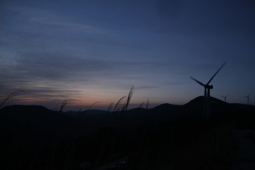 a wind turbine is silhouetted against a twilight sky