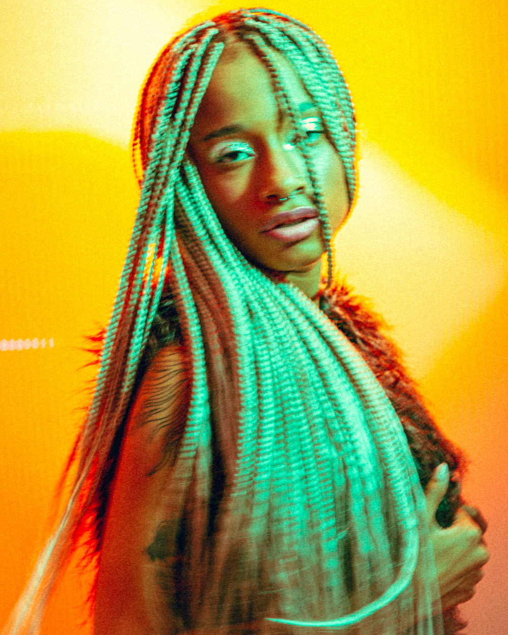 a woman with dreadlocks standing in front of an orange background