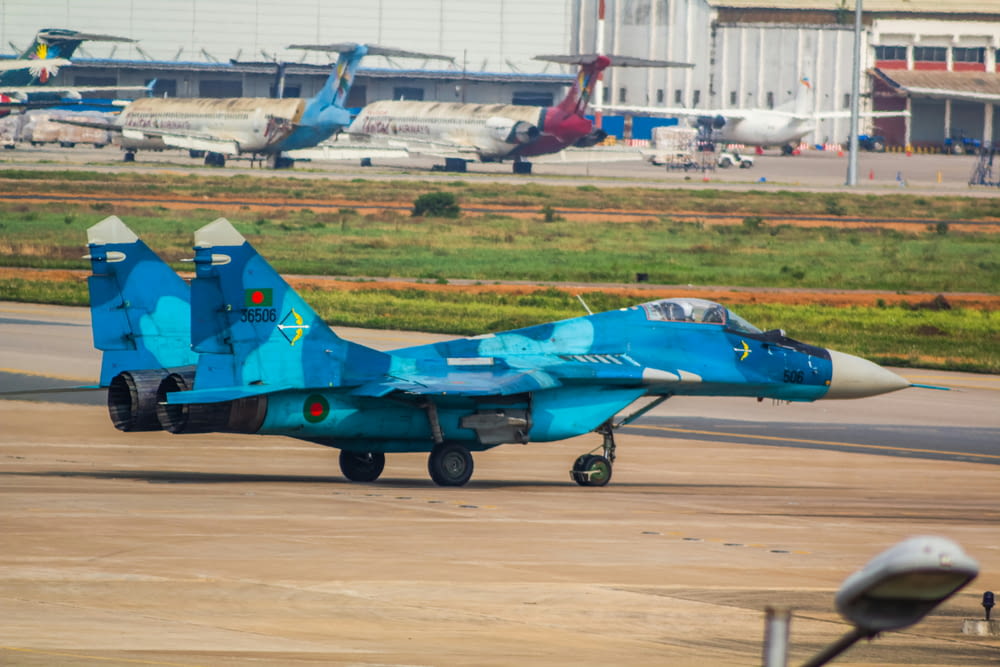 a blue fighter jet sitting on top of an airport tarmac