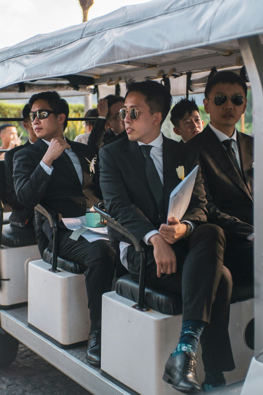 a group of men in suits sitting on a golf cart