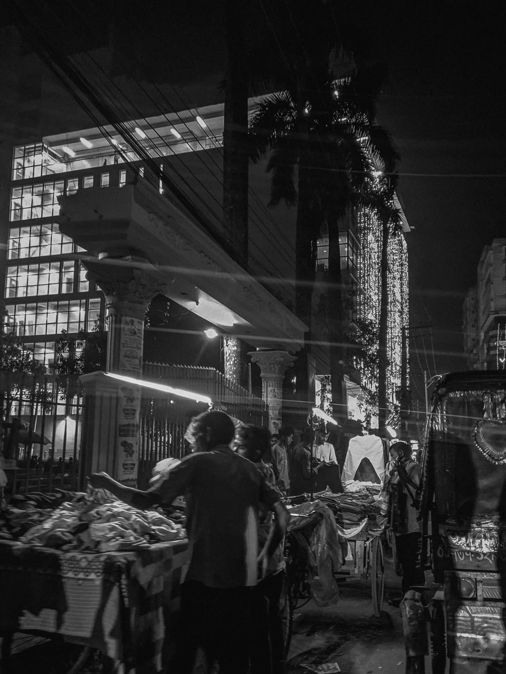 a black and white photo of people shopping at night