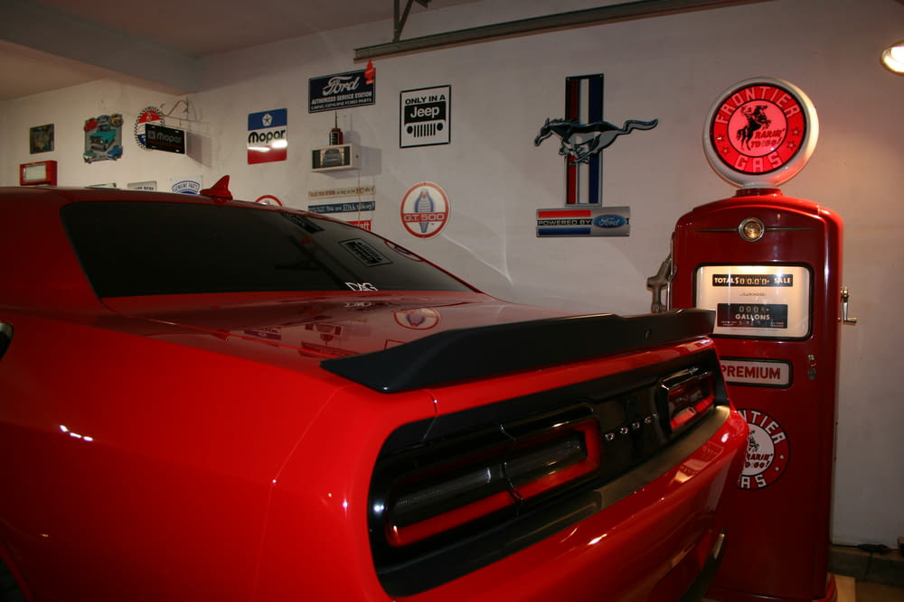 a red car parked in a garage next to a gas pump