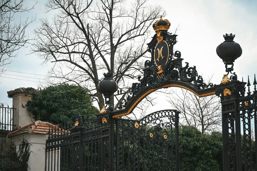 a black iron gate with a clock on top of it