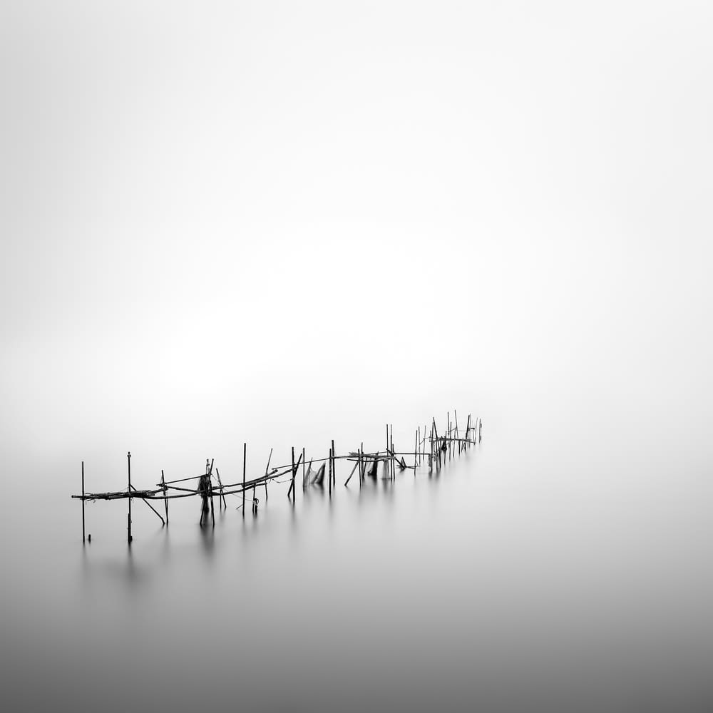 a black and white photo of a fence in the fog