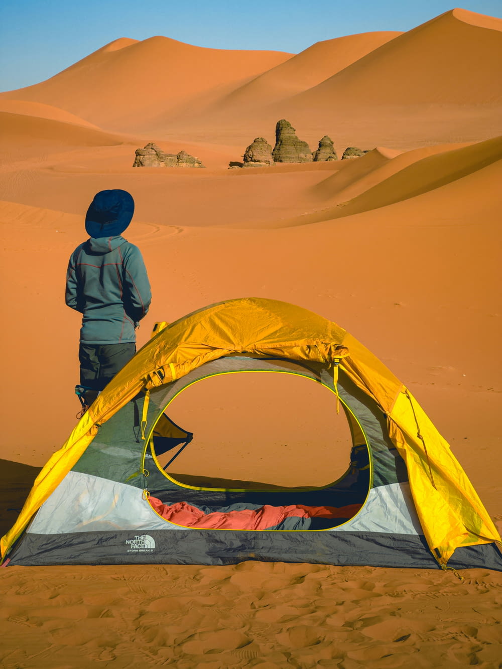 eine Person, die neben einem Zelt in der Wüste steht