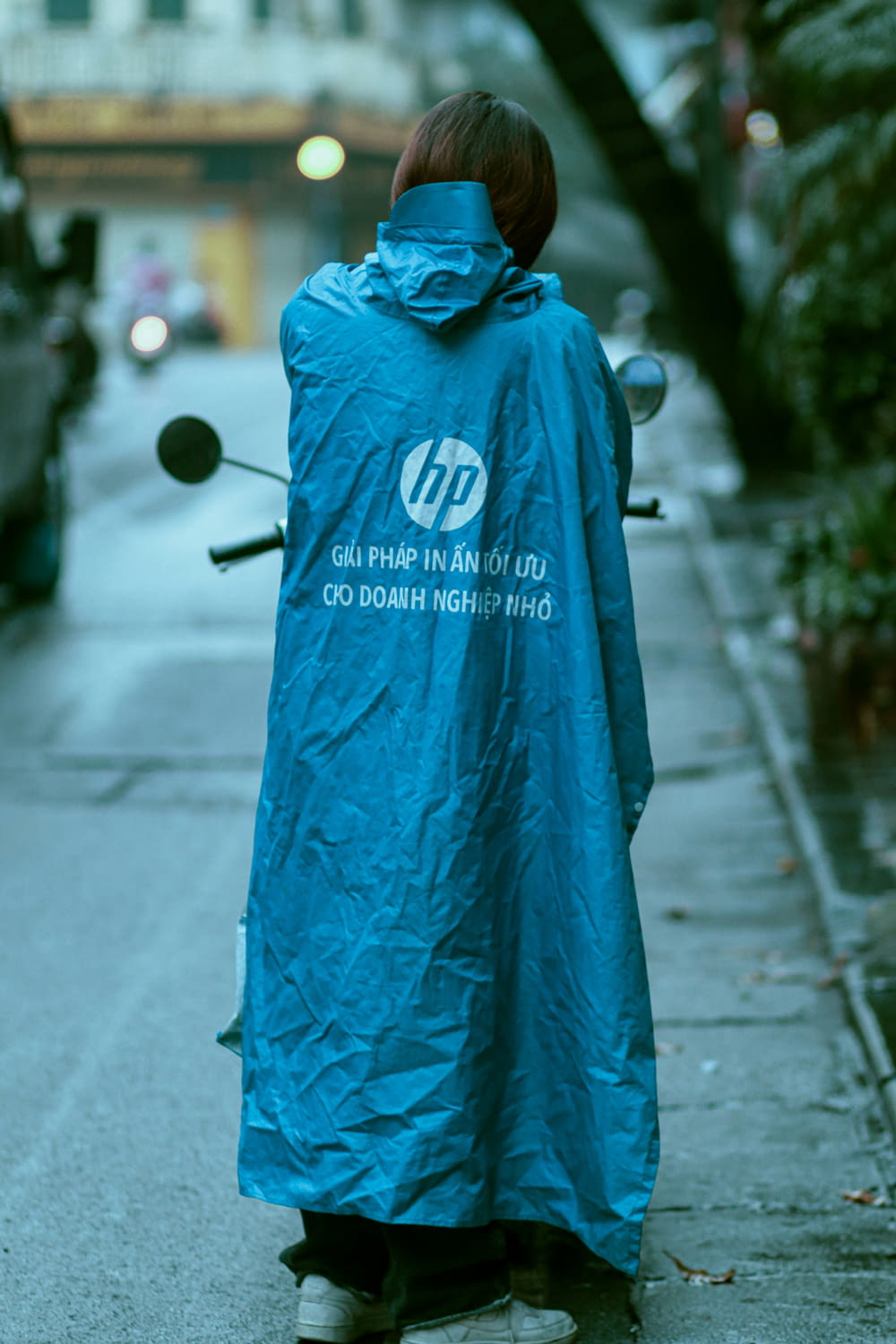 a woman in a blue raincoat is walking down the street