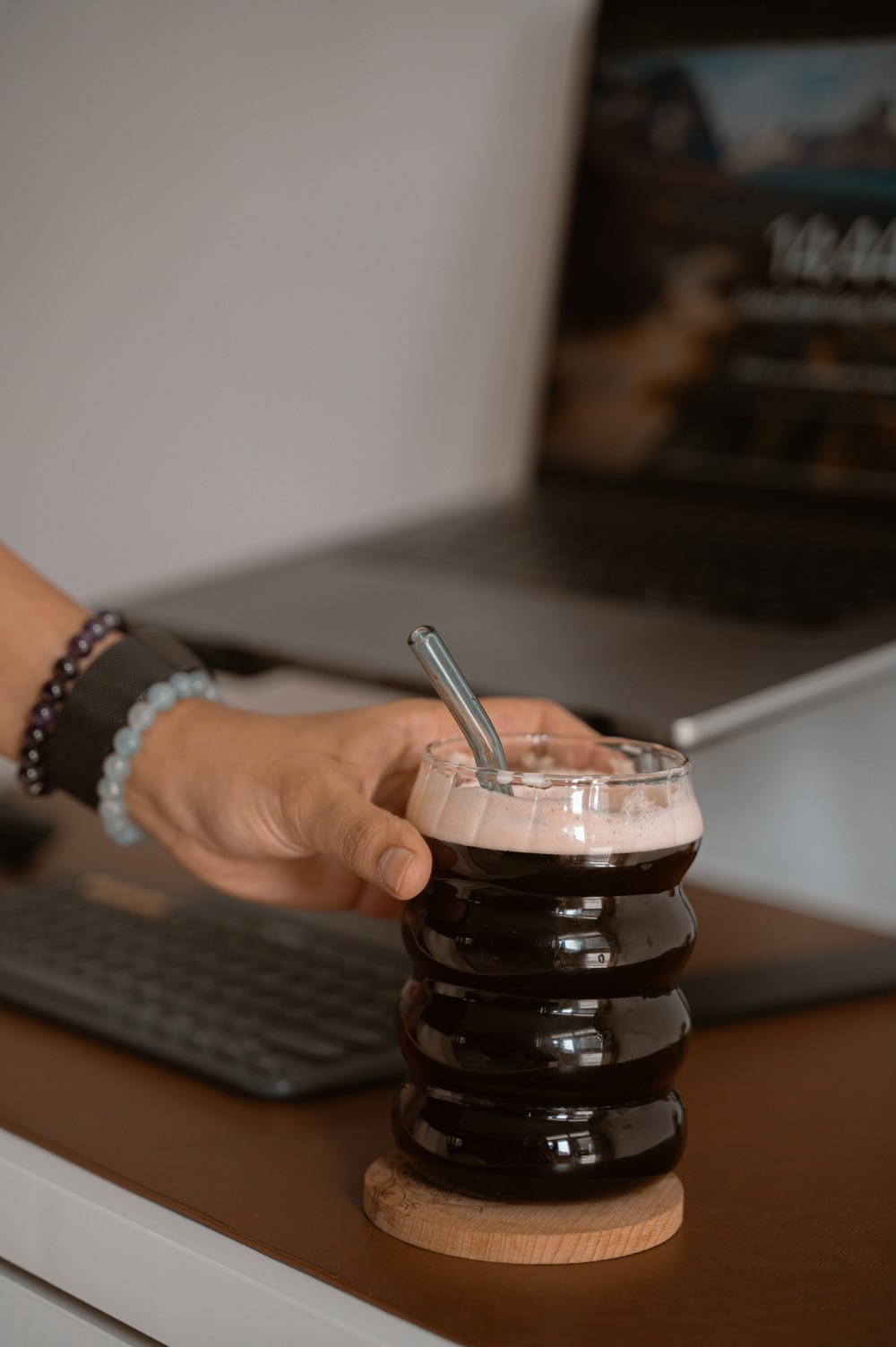 a person is holding a drink in front of a laptop