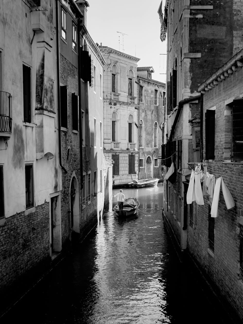 a black and white photo of a canal in a city